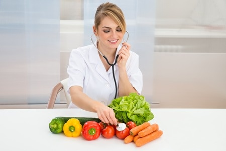 野菜に聴診器を当てて栄養成分をチェックする女性